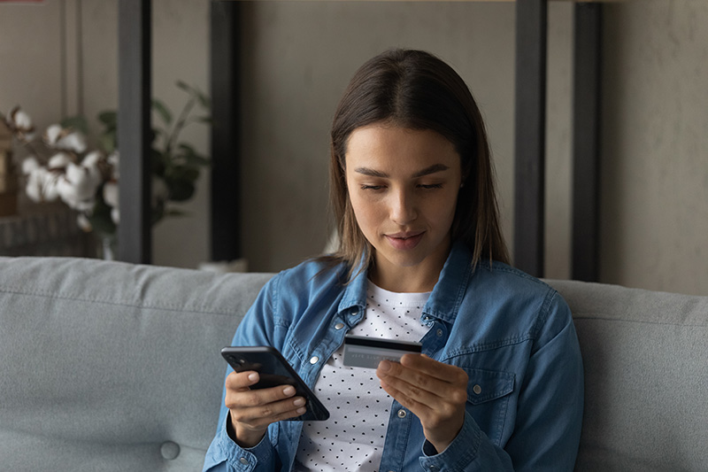 Woman looking at phone and debit card