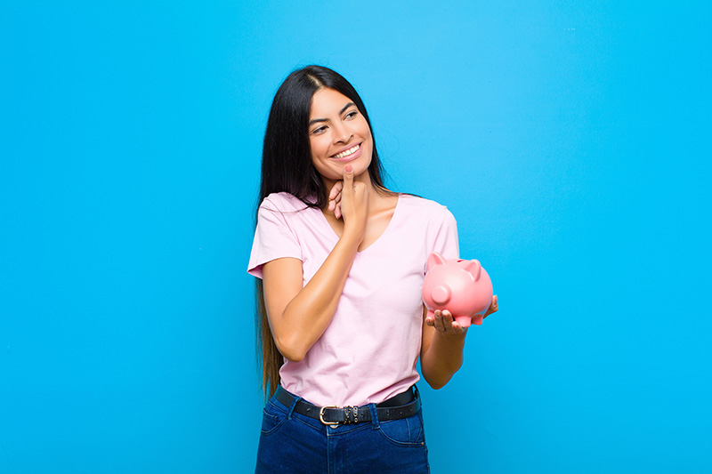 Woman holding piggy bank while thinking